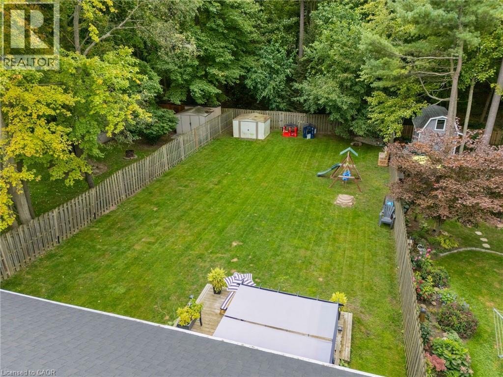 Expansive backyard featuring a manicured lawn, established privacy fencing, and mature perimeter trees - 53 Hawtrey Road, Delhi, ON