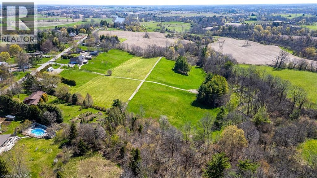 Expansive green landscape with defined grassy pathways, surrounded by mature trees and natural foliage - 47 River Road, Brantford, ON