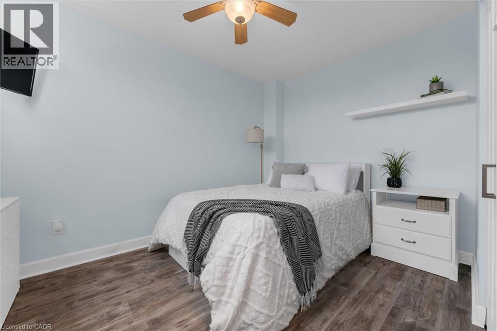 Bedroom featuring dark wood finished floors and a ceiling fan - 5 Viking Court Unit# 301, Grimsby, ON