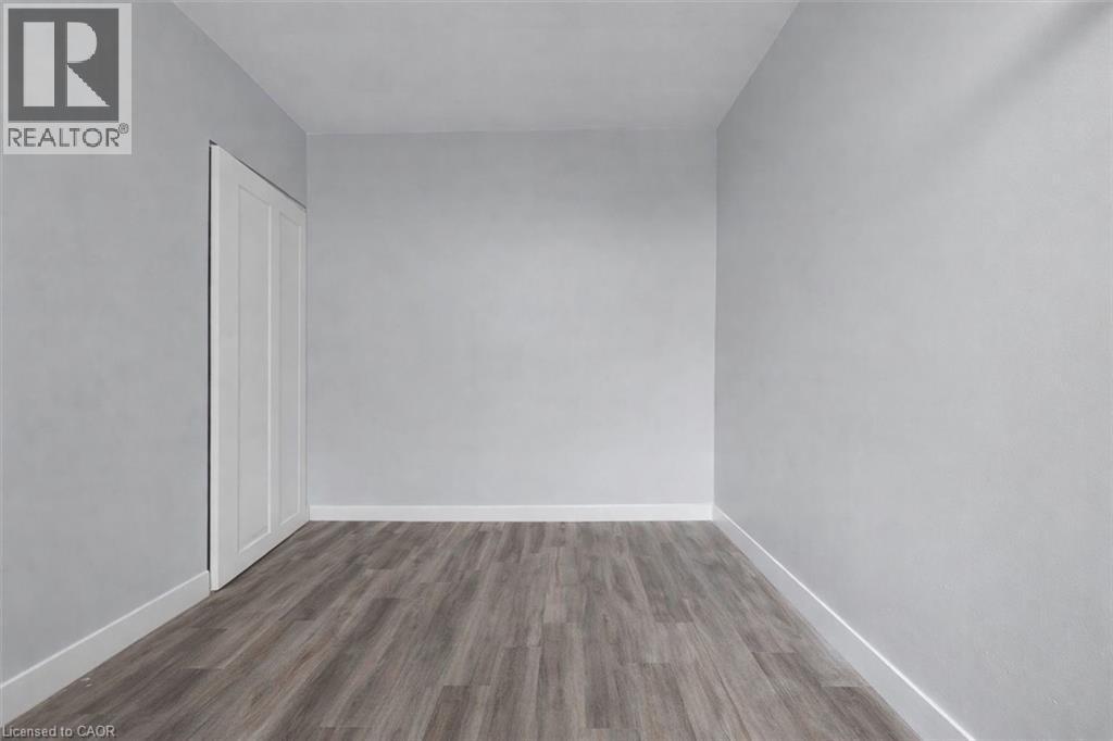 Unfurnished bedroom with dark wood-style floors and a closet - 5 Viking Court Unit# 301, Grimsby, ON
