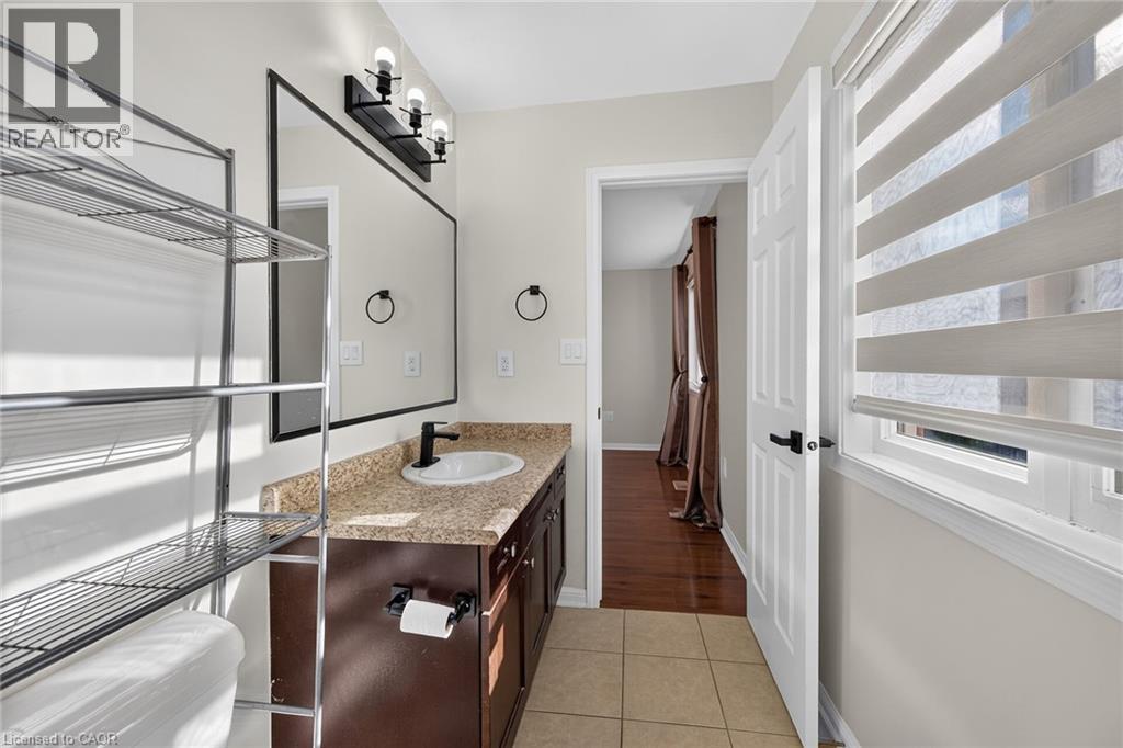 Vanity with a granite-style countertop, undermount sink, and dark wood-finish cabinetry - 103 Emick Drive, Ancaster, ON