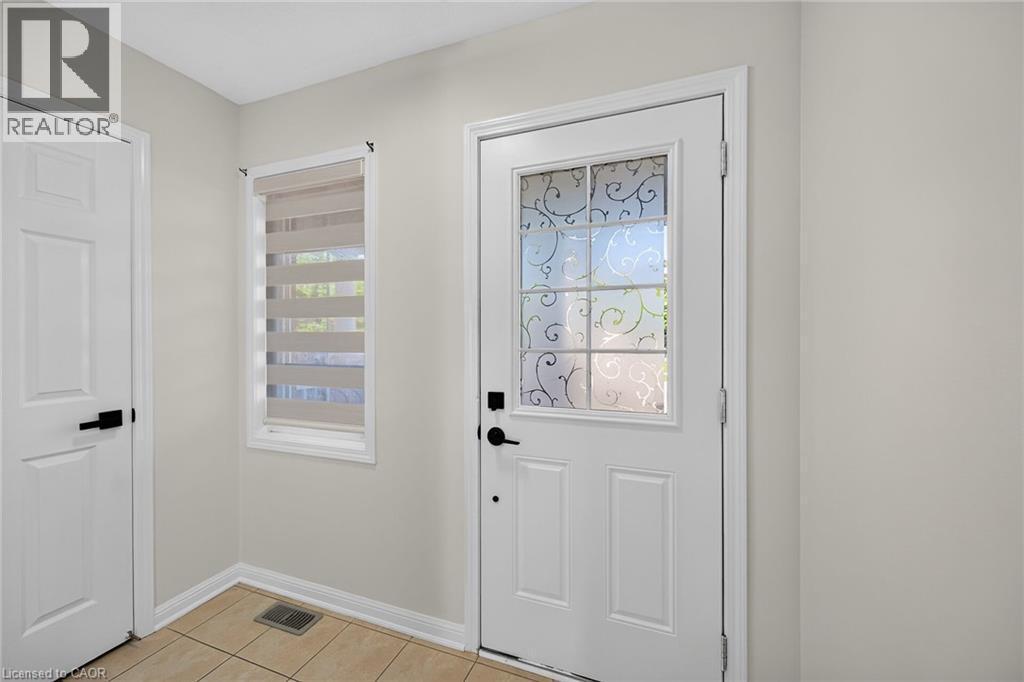 White paneled doors with matte black hardware, tiled flooring, and a decorative window - 103 Emick Drive, Ancaster, ON
