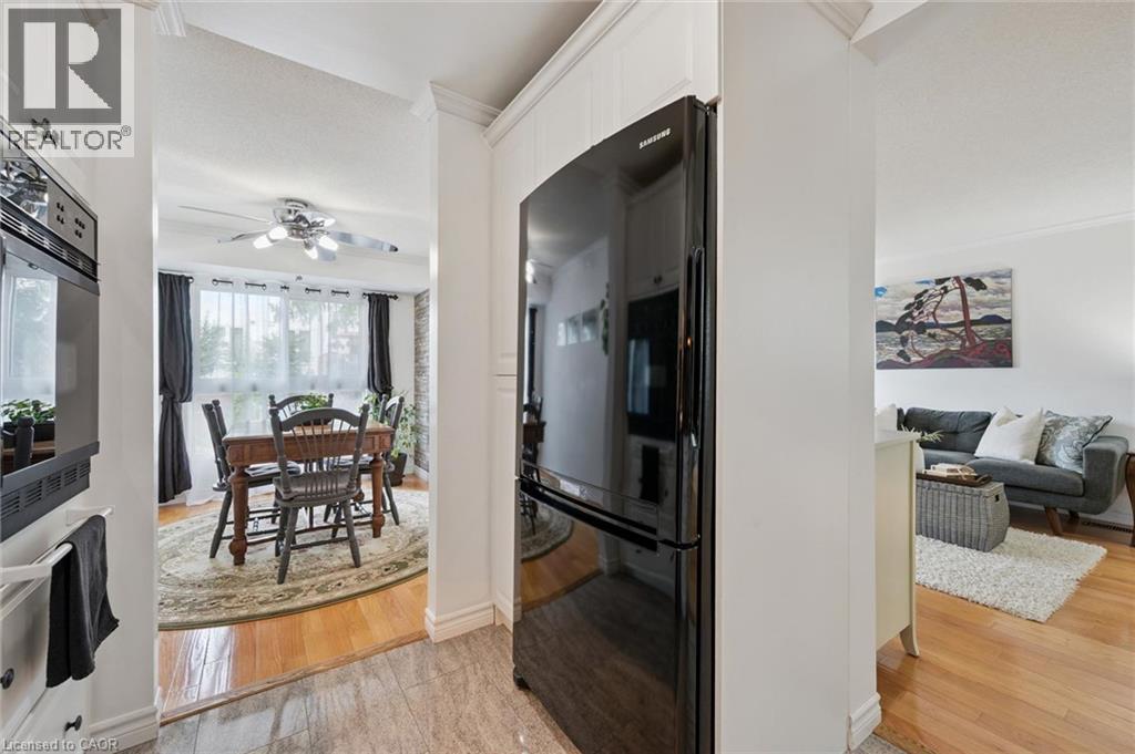 Built-in oven, black refrigerator, wood-finish flooring, crown molding, and recessed lighting - 54 Green Valley Drive Unit# 13, Kitchener, ON