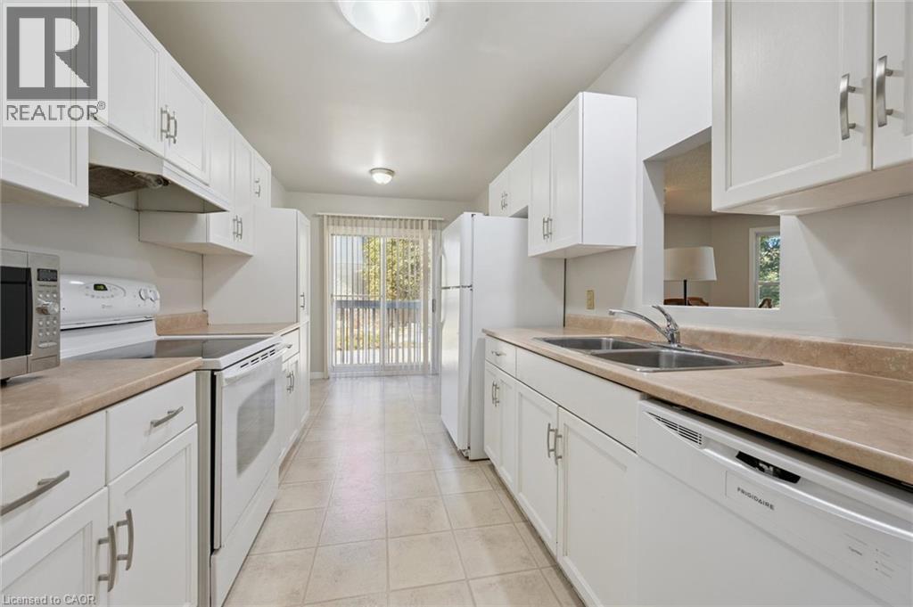 Galley kitchen featuring white cabinetry, light-toned countertops, and a double basin sink - 512 Thorndale Drive, Waterloo, ON