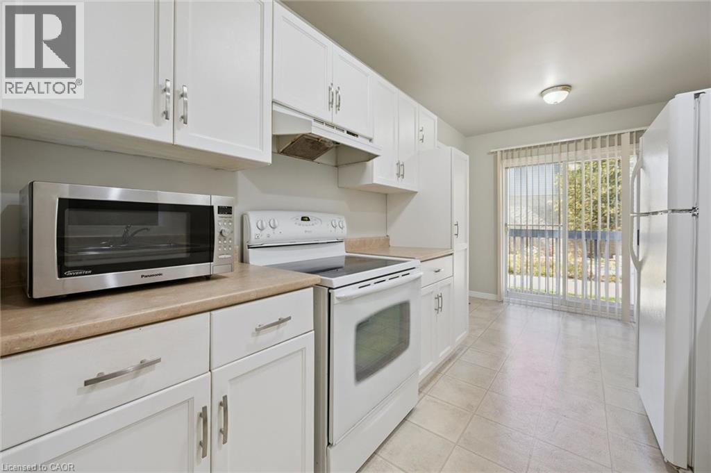 White cabinetry with silver-tone hardware, light-toned countertops, and tile flooring - 512 Thorndale Drive, Waterloo, ON