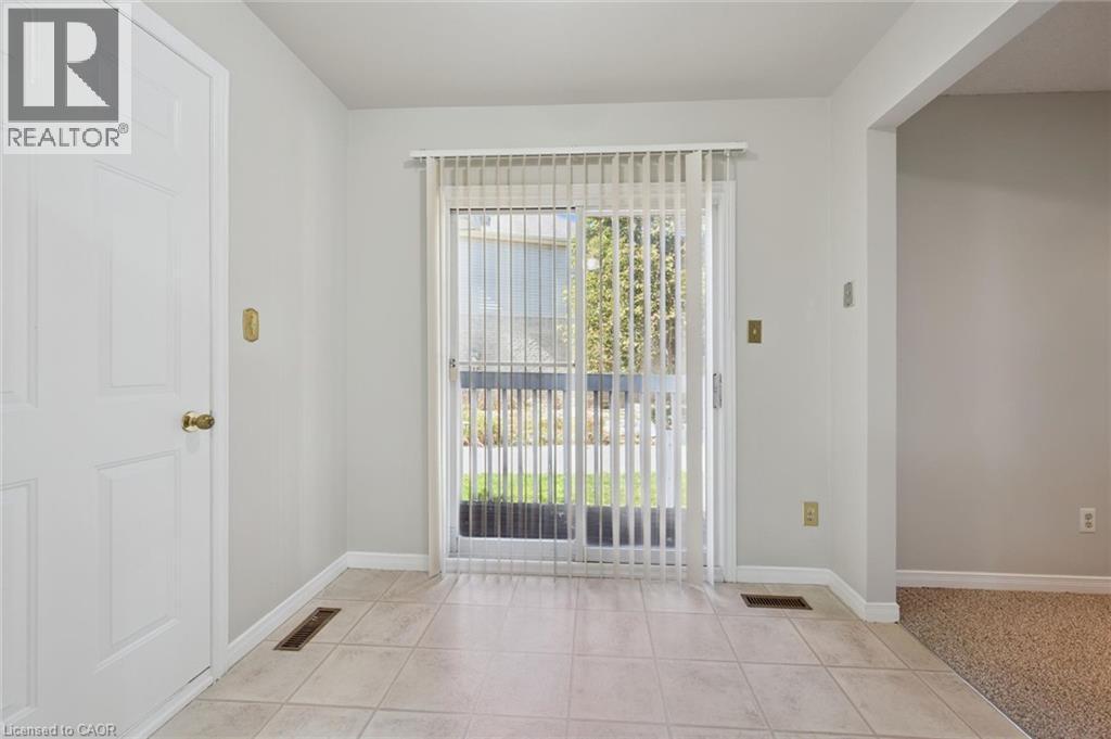 Tiled flooring extending to a sliding glass door with vertical blinds - 512 Thorndale Drive, Waterloo, ON