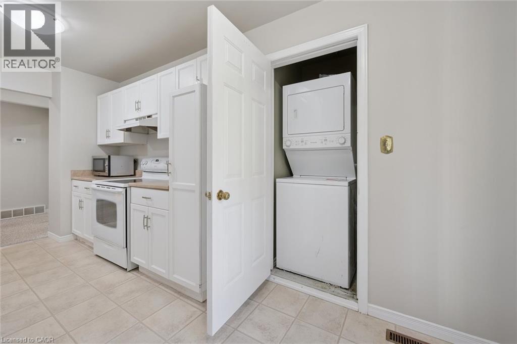 White kitchen cabinetry with stainless steel hardware, a white electric range, and a built-in microwave - 512 Thorndale Drive, Waterloo, ON