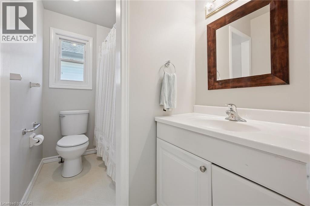 White vanity with an integrated sink and chrome faucet, set against a framed mirror with overhead lighting - 512 Thorndale Drive, Waterloo, ON