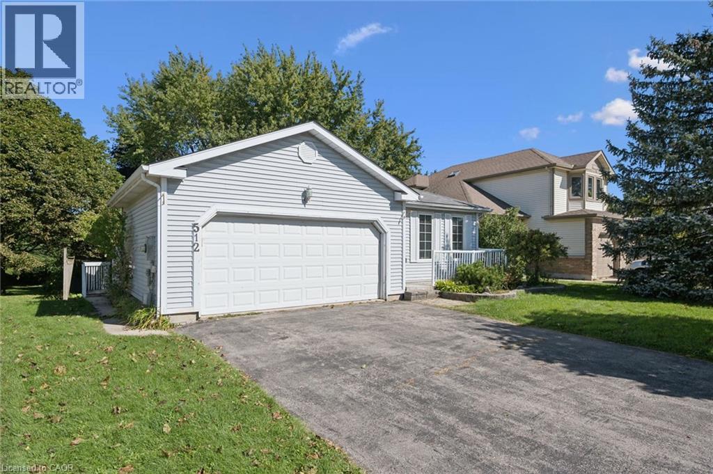 Light-colored siding exterior, attached garage with a white door, front porch with white railing, paved driveway, and mature landscaping - 512 Thorndale Drive, Waterloo, ON