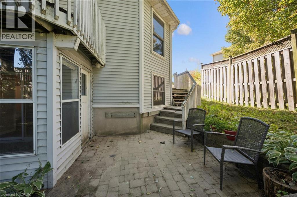 Paved patio area, wood fencing, exterior siding, and exterior stairs with wood railings - 512 Thorndale Drive, Waterloo, ON
