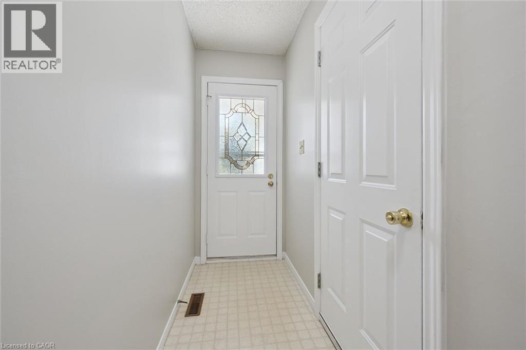 Entryway featuring a decorative glass panel door, light-toned tiled flooring, and a paneled interior door with a brass-finish knob - 512 Thorndale Drive, Waterloo, ON