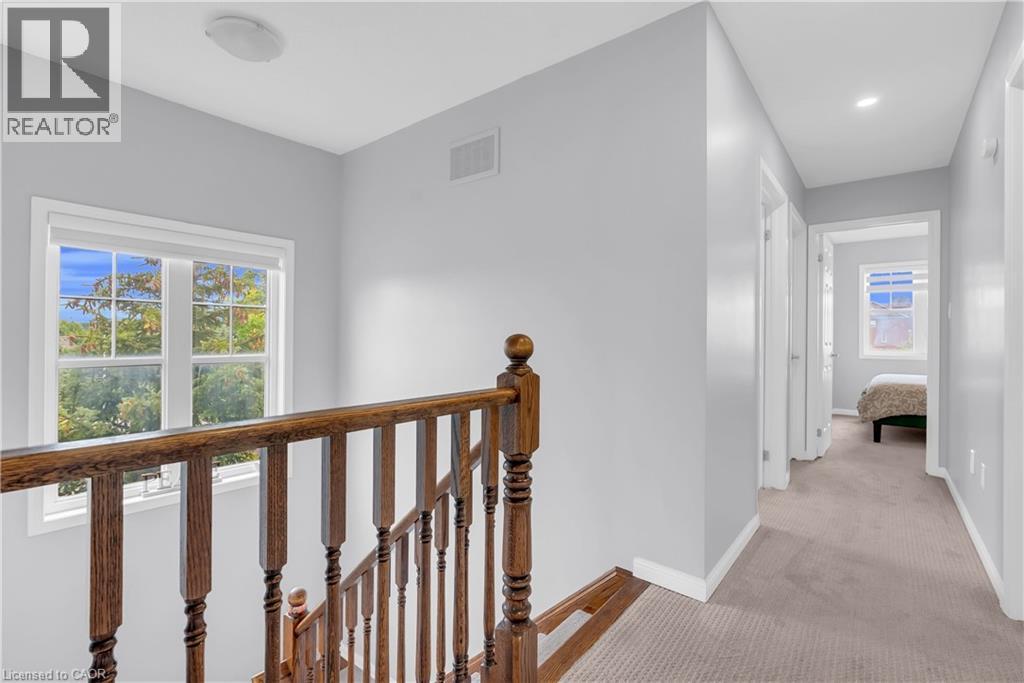 Wood banister and balusters, window with exterior scenery, overhead lighting, recessed lighting, and carpeted hallway - 2435 Coho Way, Oakville, ON