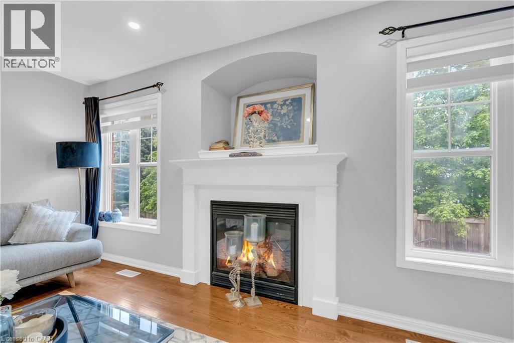Hardwood-finish flooring, recessed lighting, white trim, gas fireplace with white mantel, and arched alcove - 2435 Coho Way, Oakville, ON