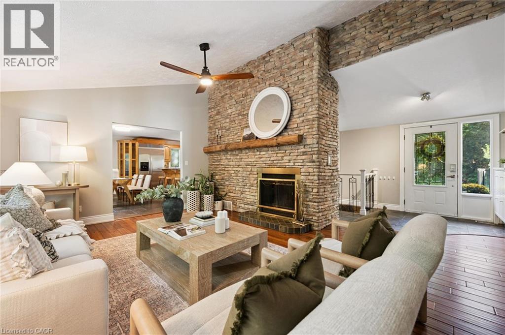 Stone-clad fireplace with a wood mantle, wood-finish flooring, a ceiling fan, and a light-filled entry with a glass-paned door - 282 Concession Rd 2, Scotland, ON