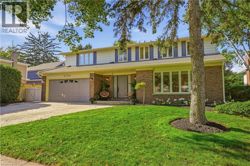 Brick exterior with light siding, front-facing garage with a paver driveway, manicured lawn with mature trees, and a covered front entry - 4159 Spruce Avenue, Burlington, ON