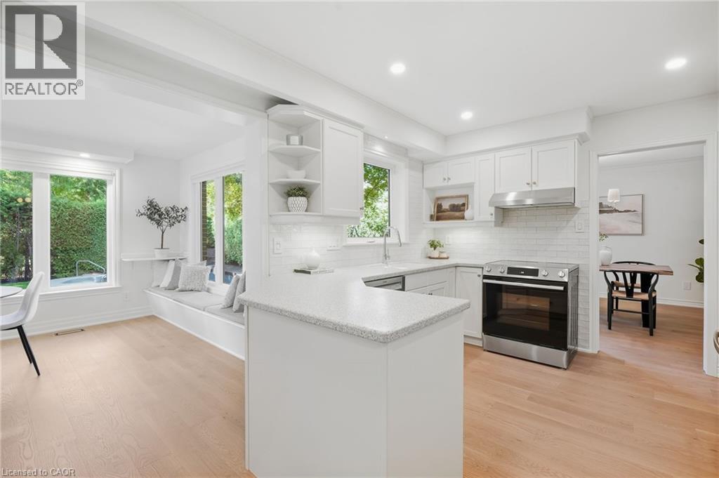 White kitchen cabinetry with stainless steel appliances, speckled countertops, and a subway tile backsplash - 4159 Spruce Avenue, Burlington, ON
