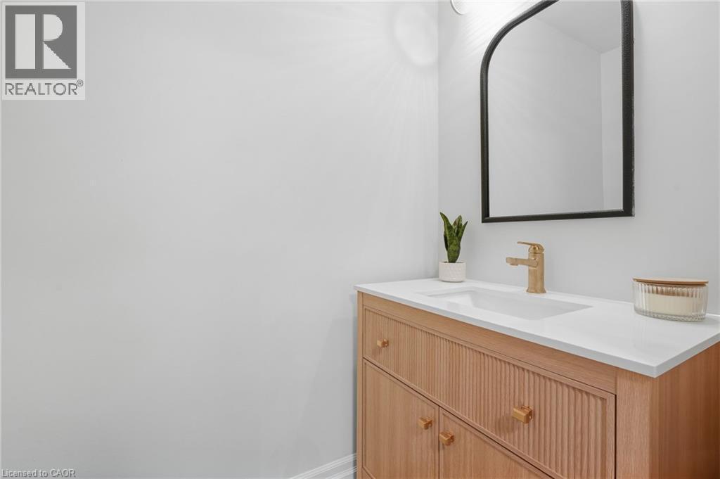 Light wood-finish vanity with fluted paneling, integrated rectangular sink, and white countertop - 4159 Spruce Avenue, Burlington, ON