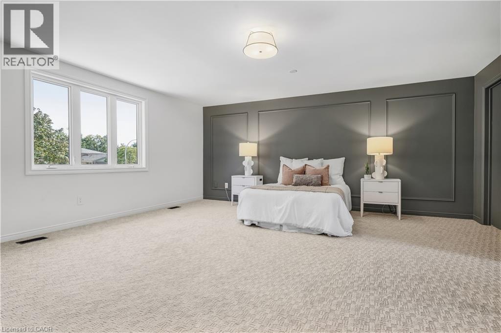 Expansive room featuring a large window, patterned carpeting, a dark accent wall with decorative molding, and an overhead flush-mount light fixture - 4159 Spruce Avenue, Burlington, ON