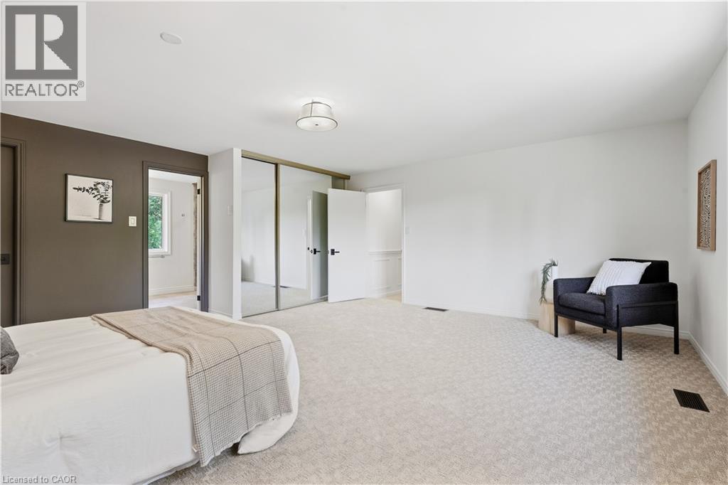 Spacious room featuring light-colored carpeting, dark accent wall, mirrored sliding closet doors, and recessed lighting - 4159 Spruce Avenue, Burlington, ON