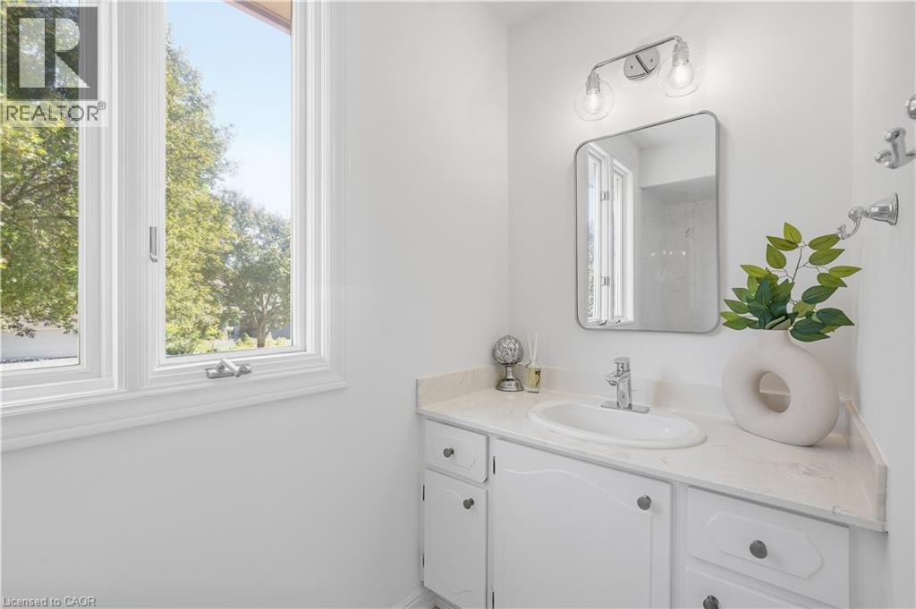White vanity with an integrated sink, polished chrome faucet, and stone-finish countertop - 4159 Spruce Avenue, Burlington, ON
