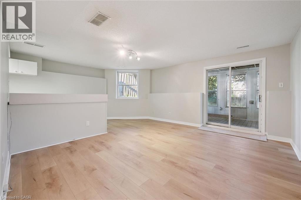 Light wood-finish flooring with a sliding glass door, overhead track lighting, and a white cabinet - 512 Thorndale Drive, Waterloo, ON