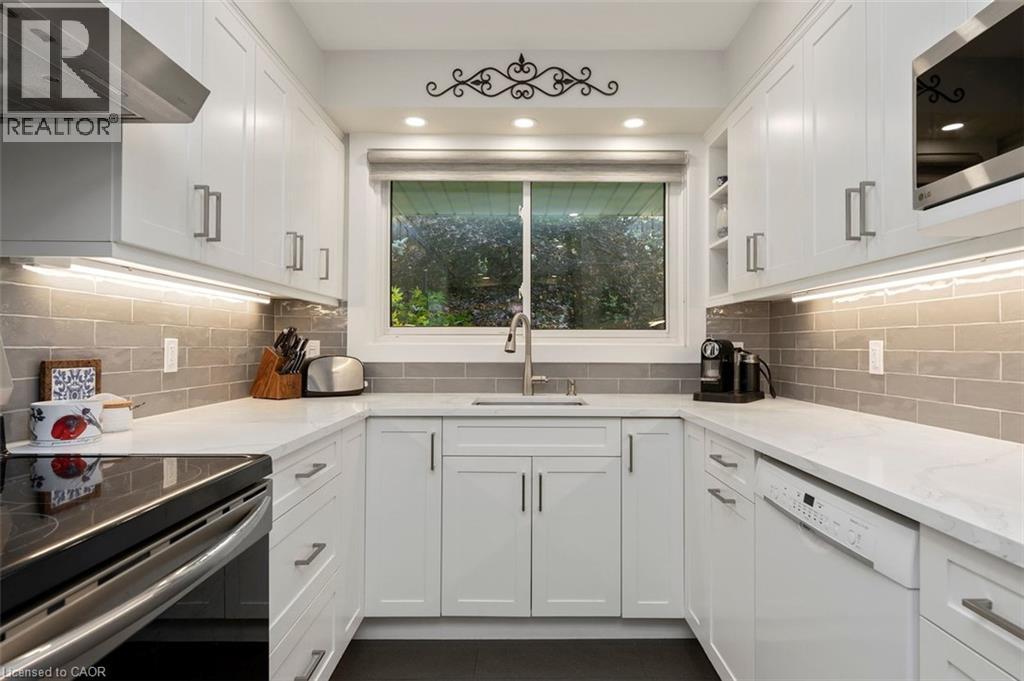 Kitchen view toward living room, open concept pass through with eat-in seating and additional cabinetry below peninsula - 200 Woodview Crescent, Ancaster, ON