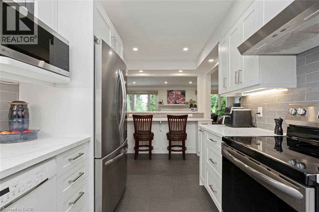 Eat-in kitchen with open concept view to family room and backyard, bonus cabinetry below peninsula, quartz counter tops - 200 Woodview Crescent, Ancaster, ON