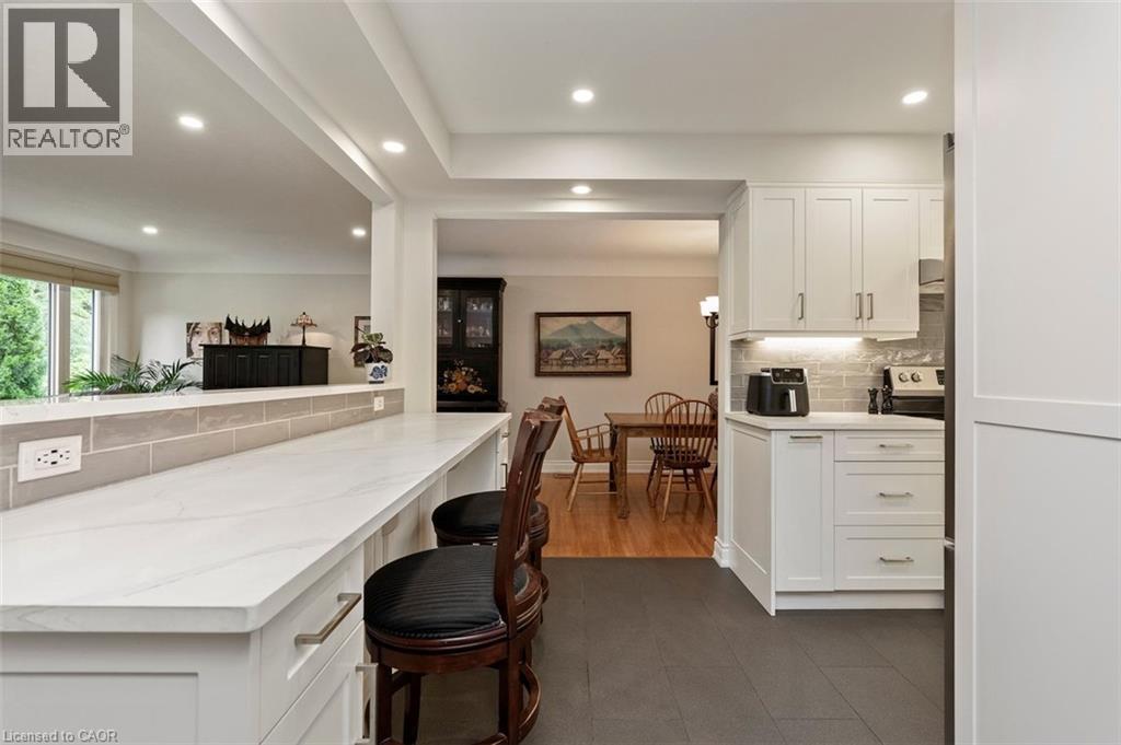 Family room with hardwood flooring, picture windows framing gas fireplace with views to backyard - 200 Woodview Crescent, Ancaster, ON