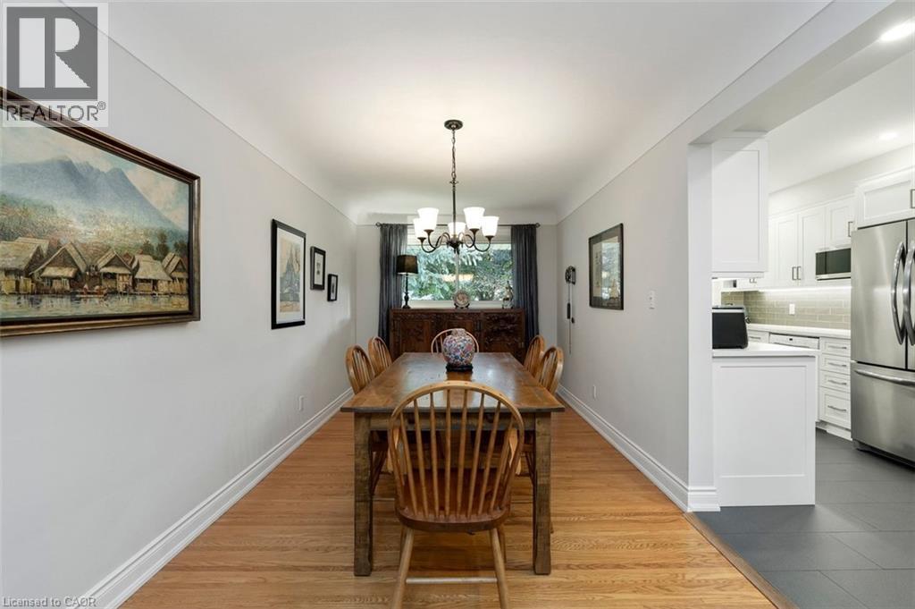Dining room view toward family room and windows to backyard, highlighting the view and mature trees - 200 Woodview Crescent, Ancaster, ON