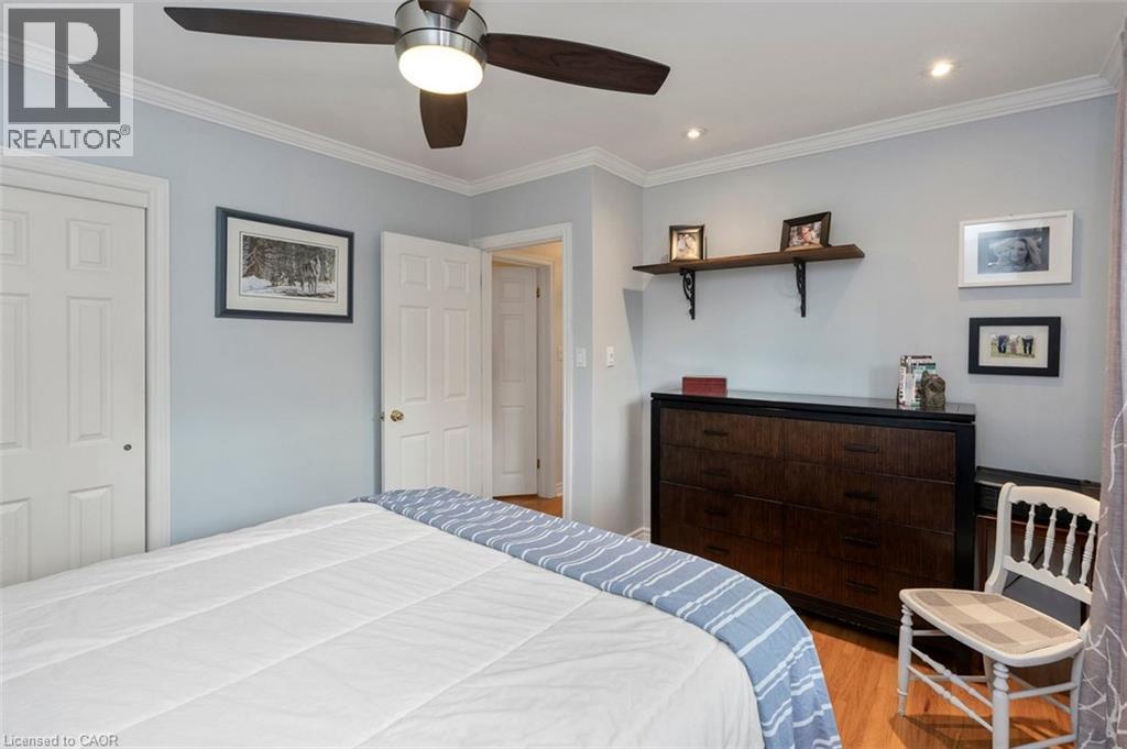 Primary bedroom with hardwood flooring, closet and view to backyard - 200 Woodview Crescent, Ancaster, ON
