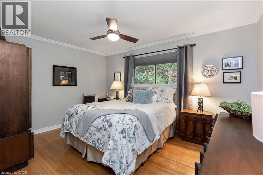 Primary bedroom with hardwood flooring, closet and view to backyard - 200 Woodview Crescent, Ancaster, ON