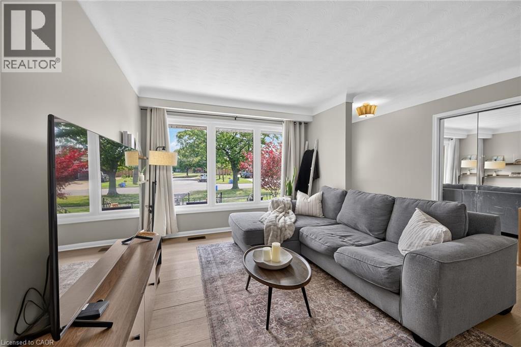 Expansive window wall with multiple panes, wood-finish flooring, crown molding, a decorative ceiling light fixture, and mirrored closet doors - 13 Allanburg Road S, St. Catharines, ON
