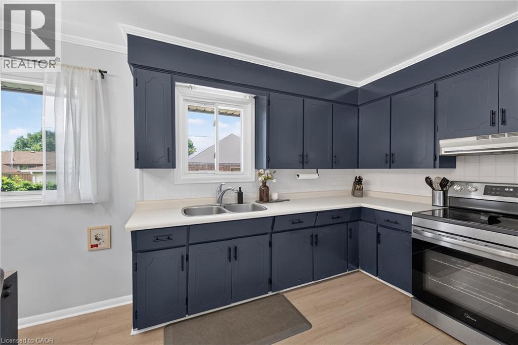 Kitchen featuring extensive navy cabinetry, a stainless steel double basin sink, white countertops, and a white subway tile backsplash - 13 Allanburg Road S, St. Catharines, ON