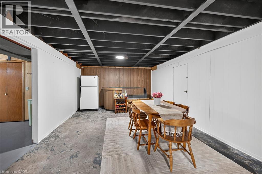 Finished basement space featuring exposed ceiling joists, white paneling, and wood paneling in the background - 13 Allanburg Road S, St. Catharines, ON