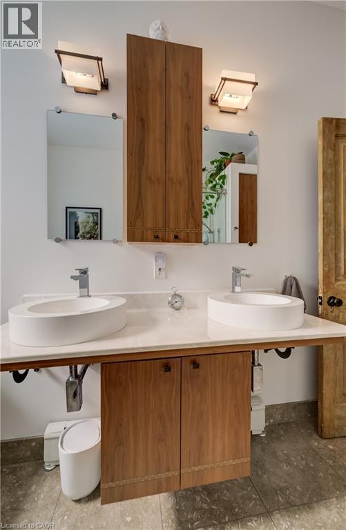 Dual vessel sinks set on a white countertop with integrated wood-finish cabinetry - 59 Allen Street W, Waterloo, ON