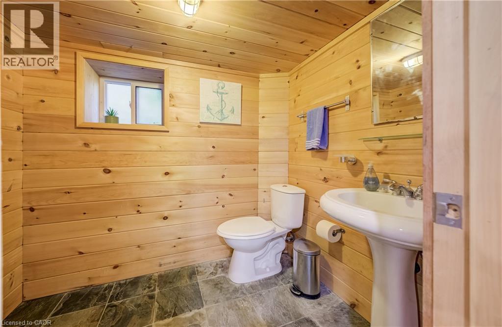 Wood-paneled walls and ceiling, pedestal sink, wall-mounted mirror, and stone-finish flooring - 59 Allen Street W, Waterloo, ON