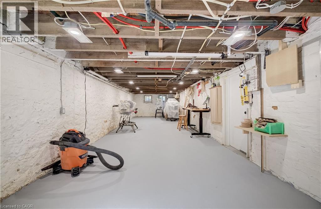 Exposed ceiling joists with visible electrical and plumbing lines, painted concrete block walls, recessed lighting, and a painted concrete floor - 59 Allen Street W, Waterloo, ON