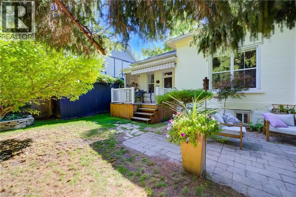 Expansive backyard featuring a stone patio, elevated wood deck with white railings, and mature trees - 59 Allen Street W, Waterloo, ON
