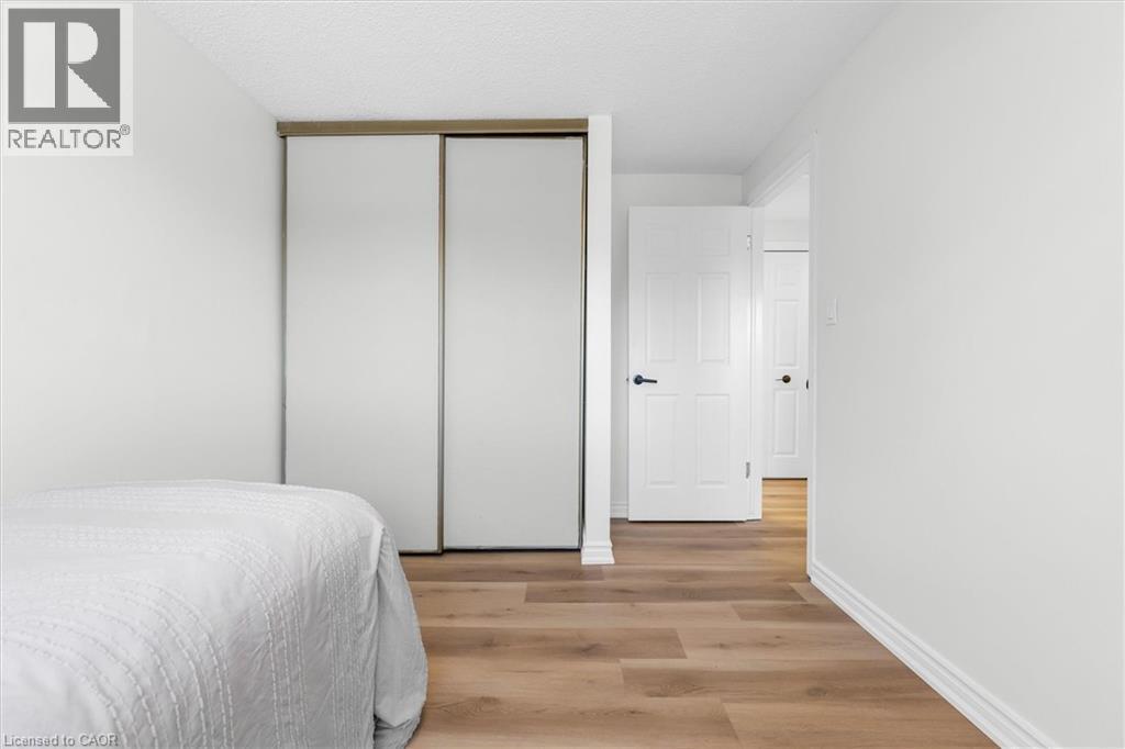 Bedroom featuring wood-finish flooring and a white sliding closet door system with a wood-tone frame - 49 Grove Avenue, St. Catharines, ON