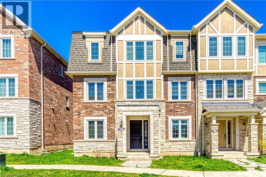 Three-story townhome featuring a stone and brick exterior, multi-pane windows, and a prominent front entrance - 212 Ellen Davidson Drive, Oakville, ON