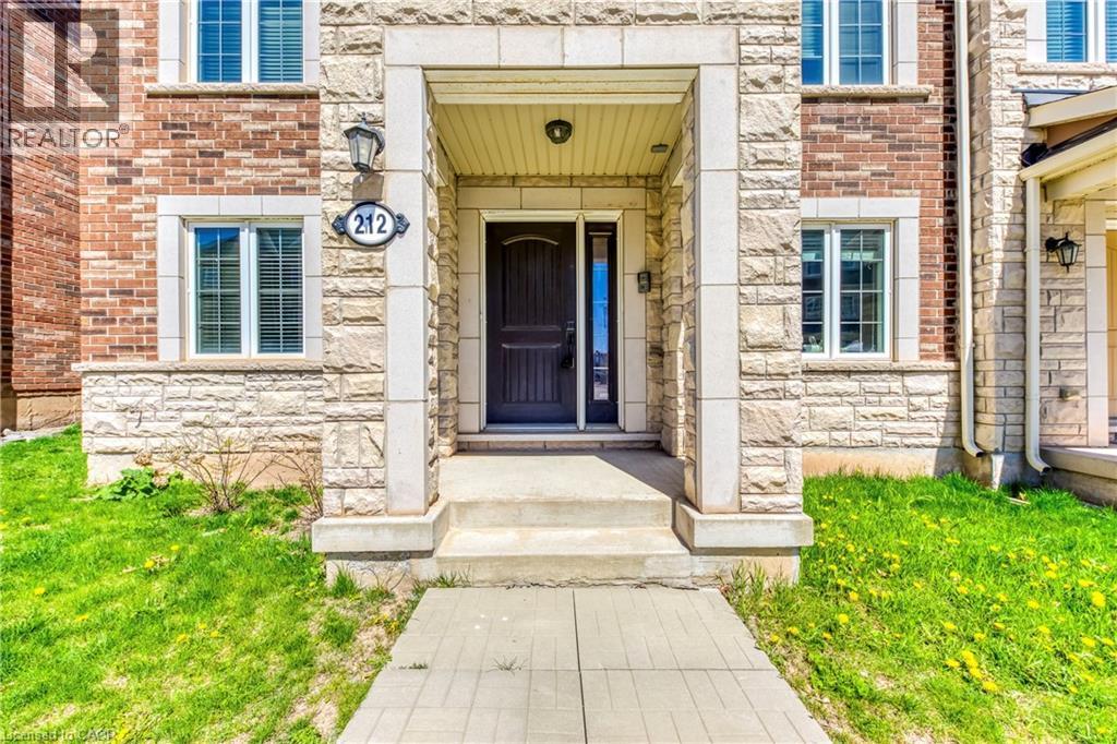 Brick and stone facade featuring a covered entry, exterior lighting, and a dark-paneled front door - 212 Ellen Davidson Drive, Oakville, ON