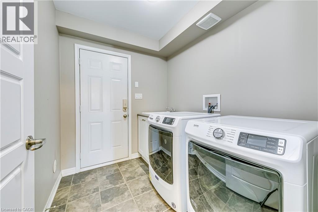 Laundry area featuring tile flooring, a utility sink, and white cabinetry - 212 Ellen Davidson Drive, Oakville, ON