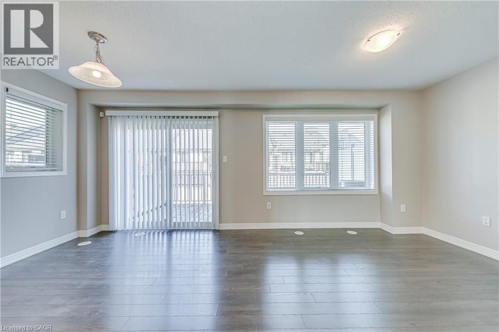 Wood-finish flooring, multiple windows with blinds, sliding glass door, and two ceiling-mounted light fixtures - 212 Ellen Davidson Drive, Oakville, ON
