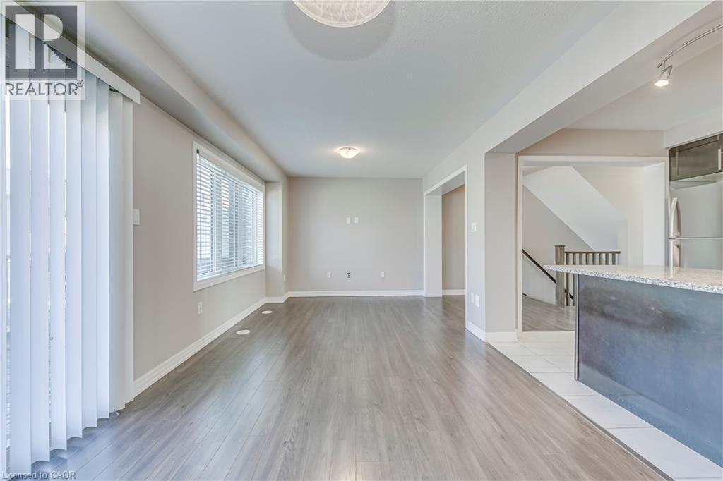 Spacious room featuring wood-finish flooring, a large window, and a glass-paneled sliding door - 212 Ellen Davidson Drive, Oakville, ON