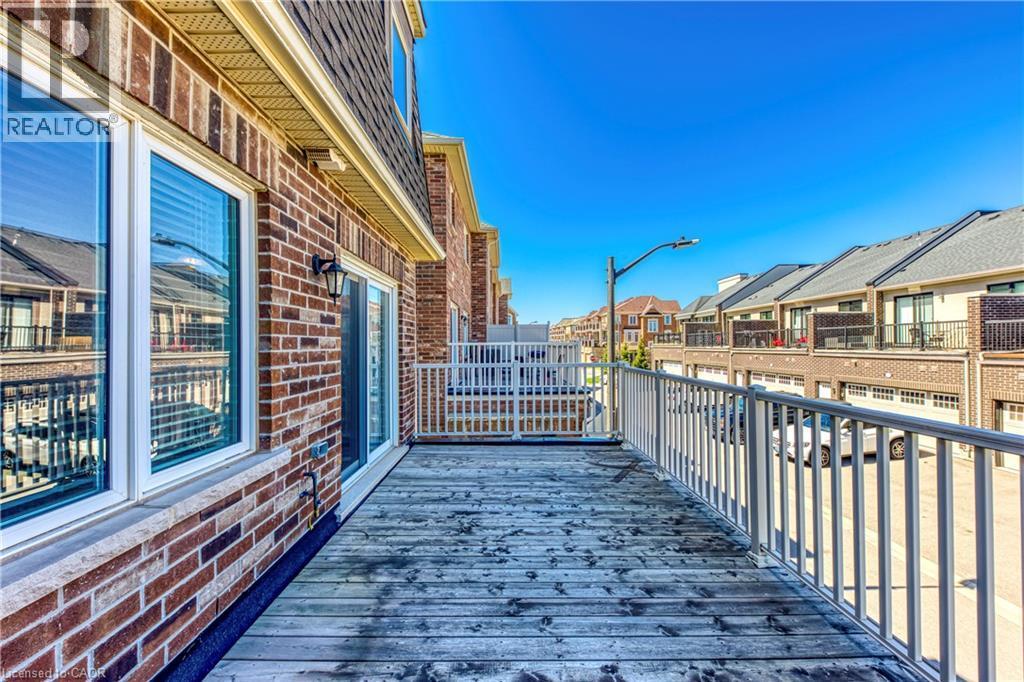 Outdoor deck with wood-finish flooring, white railing, and a sliding glass door - 212 Ellen Davidson Drive, Oakville, ON