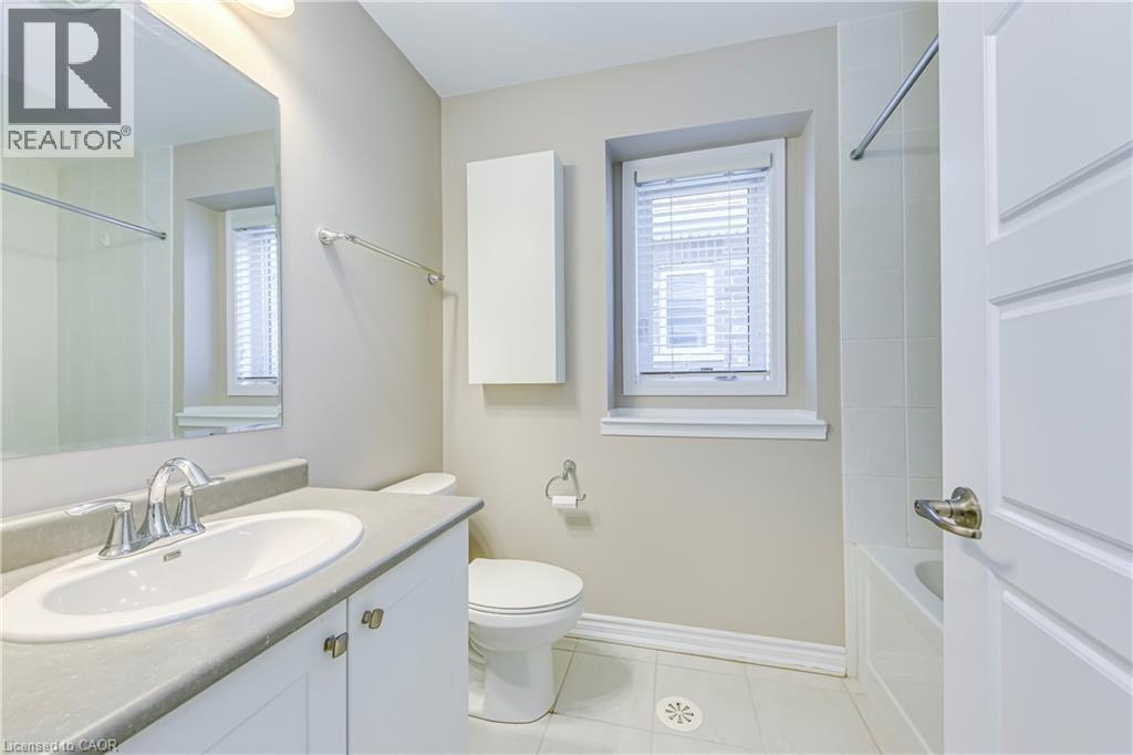 Bathroom featuring a vanity with an integrated sink, a wall-mounted storage cabinet, and a bathtub with tiled surround - 212 Ellen Davidson Drive, Oakville, ON