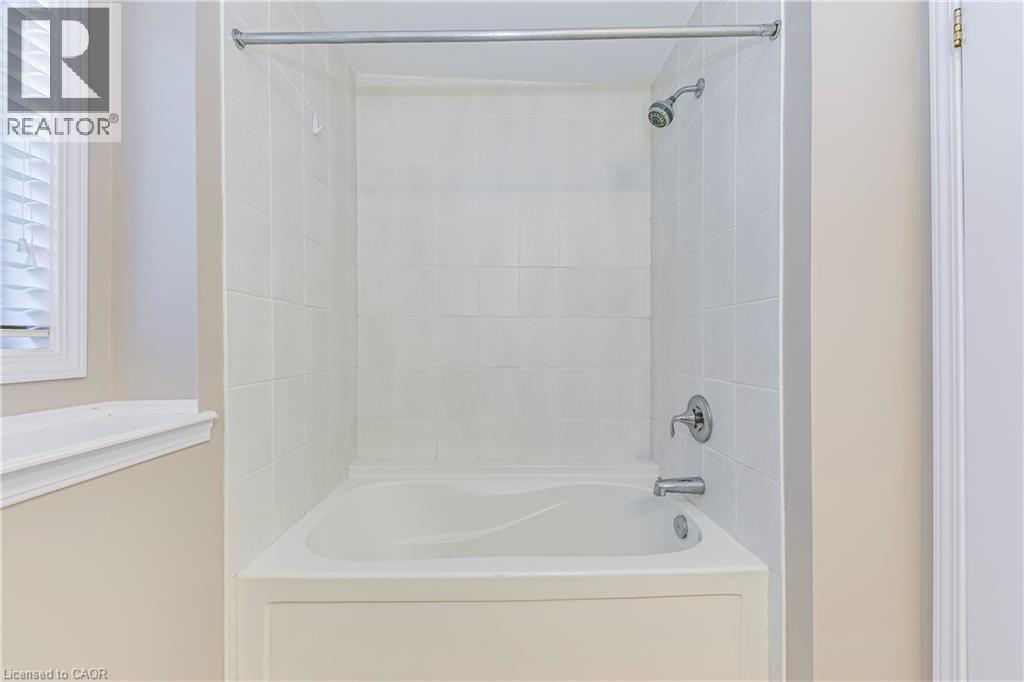 Bathtub and shower combination featuring white subway tile surround, chrome fixtures, and a white window with blinds - 212 Ellen Davidson Drive, Oakville, ON