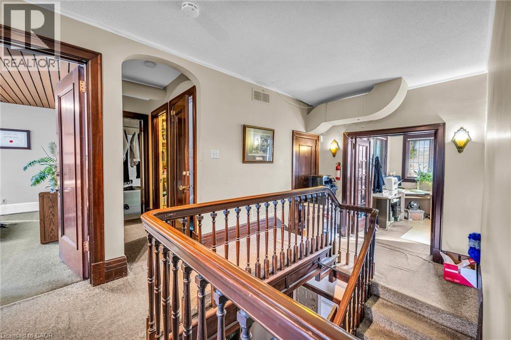 Hardwood staircase with ornate balusters and handrail, arched doorway, and built-in wall sconces - 414 Main Street E, Hamilton, ON