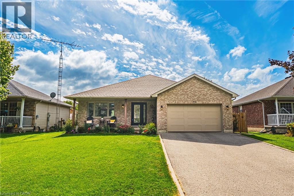 Brick exterior with an attached garage, paved driveway, and covered front porch - 915 St George Street, Port Dover, ON