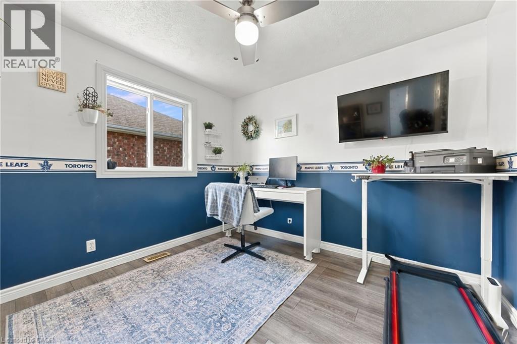 Wood-finish flooring with white baseboards, bright white walls with a blue accent, and a large window providing ample natural light - 915 St George Street, Port Dover, ON
